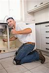 Plumber fixing under the sink in the kitchen