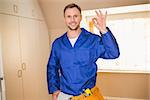 Handyman smiling at camera in tool belt in a new house