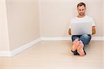 Focused man using laptop on floor in his new home