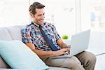 Man using laptop on couch in bright living room