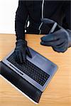 Mid section of a burglar using laptop and smartphone on white background