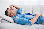 Man with grey hair relaxing on the couch at home in the living room