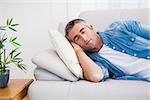 Man with grey hair sleeping on the couch at home in the living room