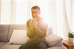 Smiling man enjoying hot drink at home in the living room