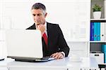 Focused businessman in suit using his laptop in his office