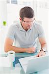 Casual businessman using his laptop at desk in his office