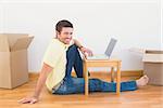 Casual man sitting on floor using laptop on the coffee table at home in the living room