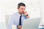 Confused businessman looking at his laptop in his office