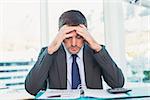 Stressed businessman with head in hands in his office