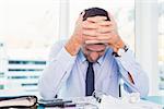 Stressed businessman with head in hands in his office