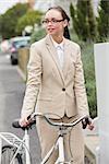 Young businesswoman standing with bike outside in the city