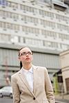 Young businesswoman looking up wearing glasses outside in the city