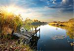 Old pier on autumn river at sunset