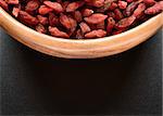 Wooden Bowl Full of Dried Goji Berries on the Black Table. Healthy Diet