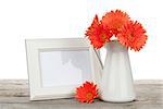 Orange gerbera flowers and photo frame on wooden table on white background