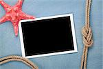 Blank photo frame with starfish and ship rope over blue wooden background