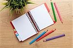 Office table with flower, blank notepad and colorful pencils. View from above with copy space