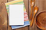 Wood kitchen utensils over wooden table background with notepad for copy space