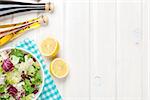 Fresh healthy salad and condiments over white wooden table. View from above with copy space