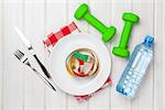 Dumbells and healthy food over wooden background. View from above