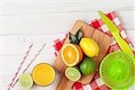 Citrus fruits and glass of juice. Oranges, limes and lemons. Over white wood table background with copy space