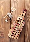 Wine bottle shaped corks and corkscrew over rustic wooden table background. View from above