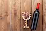 Red wine bottle and glass shaped corks. Over rustic wooden table background with copy space