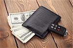 Money cash wallet and car remote key on wooden table