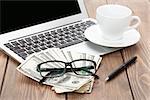 Office table with pc, coffee cup, glasses and money cash