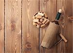 White wine bottle, bowl with corks and corkscrew. View from above over rustic wooden table background