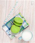 Cup of milk and macarons on white wooden table