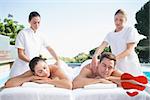 Calm couple enjoying couples massage poolside against heart