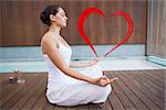 Peaceful brunette in white sitting in lotus pose  against heart