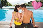 Couple sitting by swimming pool on a sunny day against heart