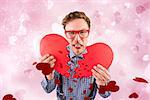 Geeky hipster holding a broken heart  against valentines heart design