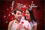 Woman surprising boyfriend with gift against valentines heart design