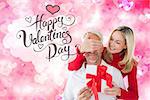 Loving couple with gift against digitally generated girly heart design