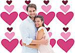 Attractive young couple hugging and smiling at camera against valentines day pattern