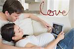 Prospective parents looking at ultrasound scan on tablet pc against love spelled out in petals