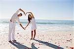 Loving couple forming heart shape with arms against red love hearts