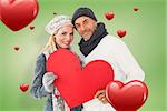 Smiling couple in winter fashion posing with heart shape against green vignette