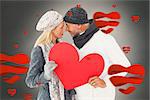 Smiling couple in winter fashion posing with heart shape against white background with vignette