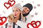 Smiling couple in winter fashion posing against hearts