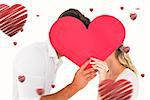 Attractive young couple kissing behind large heart against hearts