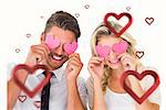 Attractive young couple holding pink hearts over eyes against hearts