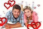 Attractive young couple smiling at camera against hearts