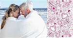 Couple sitting on the beach under blanket smiling at each other against valentines pattern