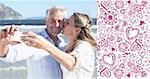 Married couple at the beach together taking a selfie against valentines pattern
