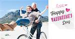 Carefree couple going on a bike ride on the beach  against cute valentines message