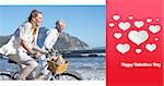 Smiling couple riding their bikes on the beach against happy valentines day